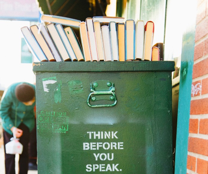 Libros apilados sobre un bote de basura.