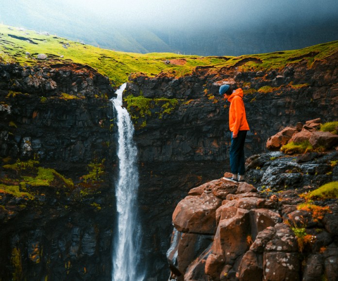 Persona en un punto alto de una cascada.