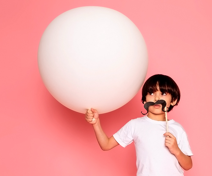 niño con un bigote de papel sujetando un globo blanco