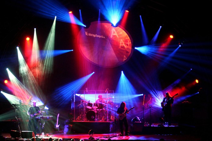 La banda presentando su Pink Floyd Experience bajo luces brillantes. 