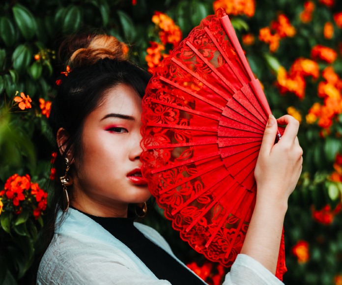 Mujer asiática con un abanico rojo.