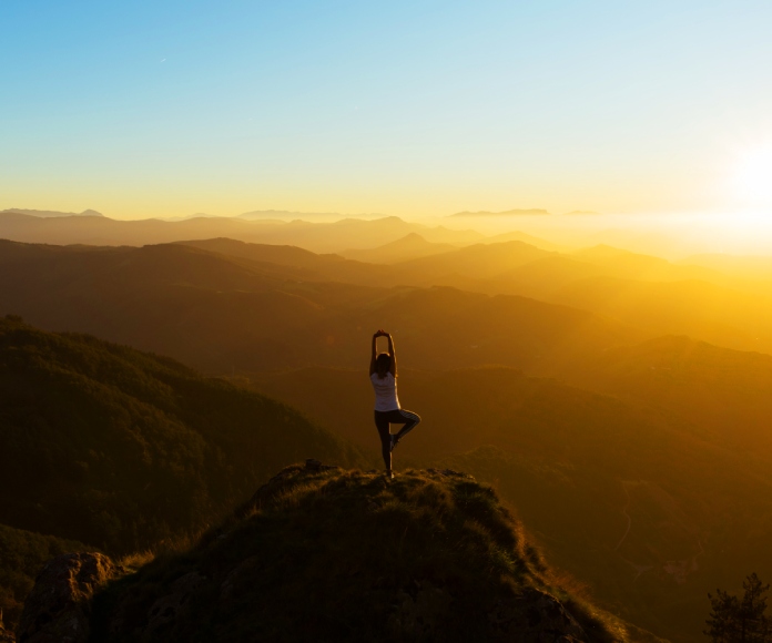 Persona haciendo yoga en una montaña.