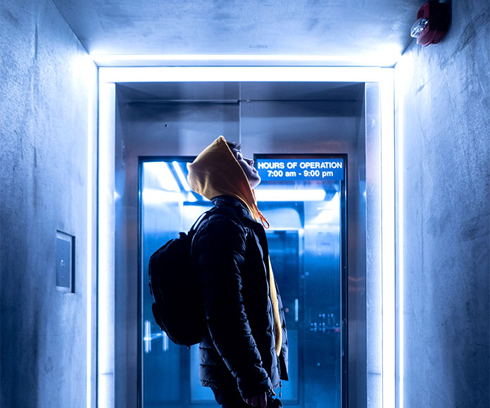 Hombre joven abrigado en un scape room o pasillo oscuro con iluminacion azul