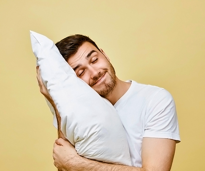 chico sonriente abrazando una almohada