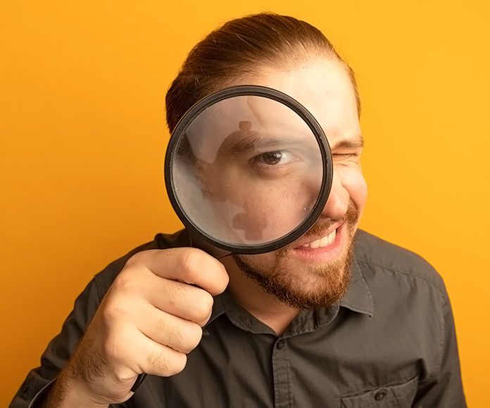 hombre joven mirando a través de una lupa