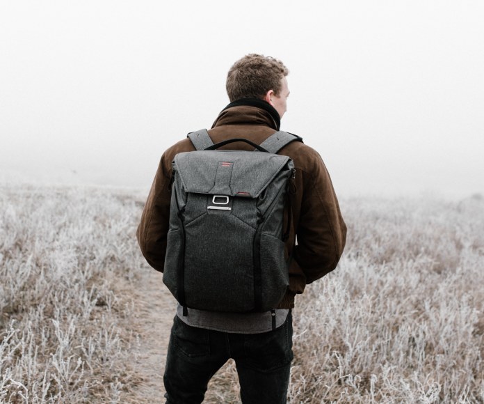 Hombre de espaldas con morral en la naturaleza