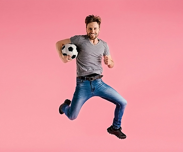 hombre saltando con un balón de fútbol bajo el brazo