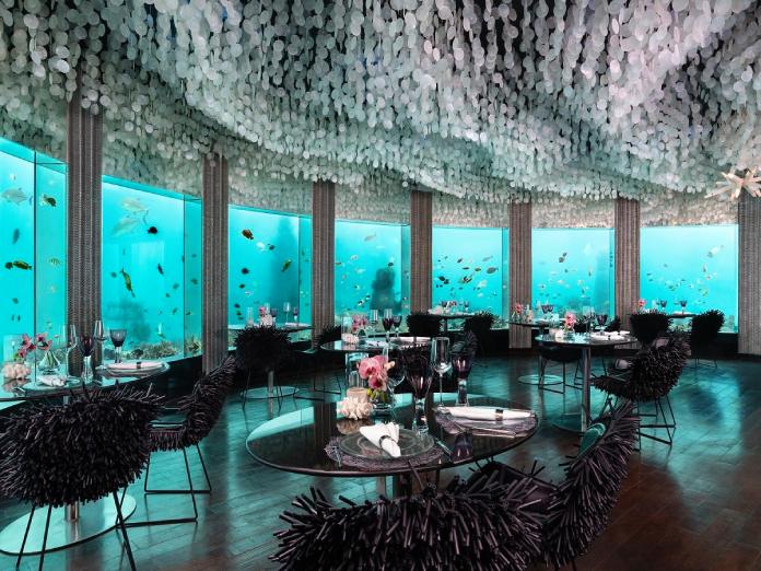 Restaurante bajo el agua con paredes de vidrio que dan al océano.