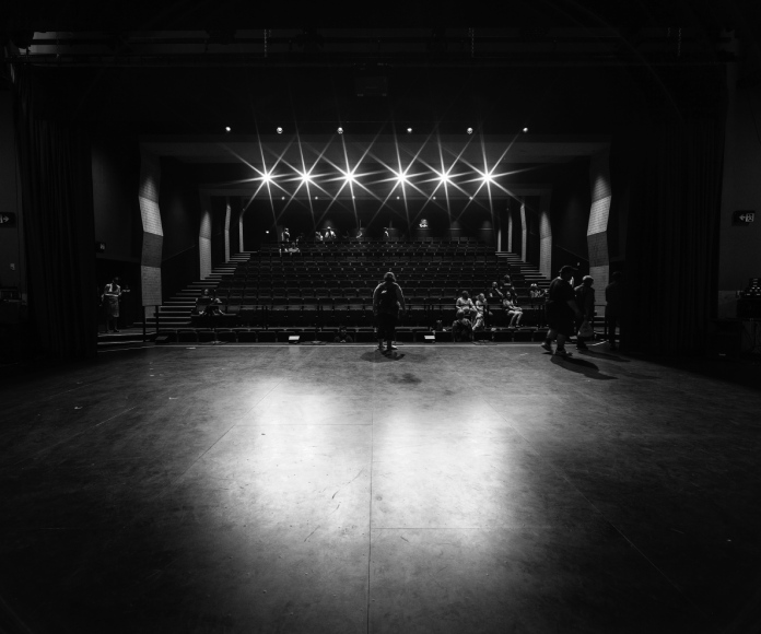 Persona en un escenario teatral con reflectores encendidos.