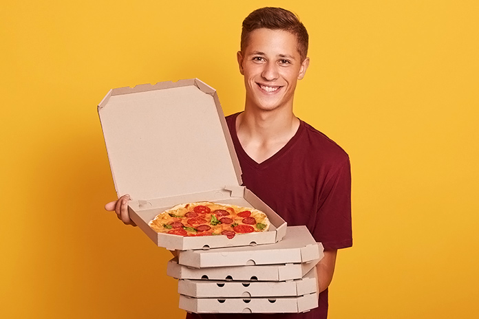 chico joven con varias cajas de pizza en las manos