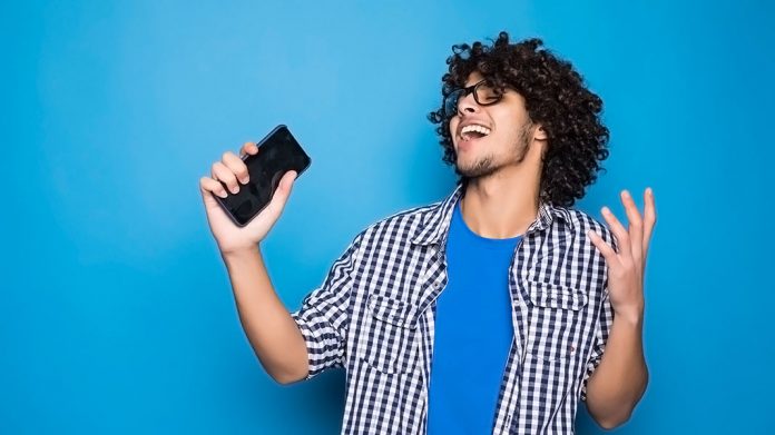 chico feliz sujetando un teléfono móvil