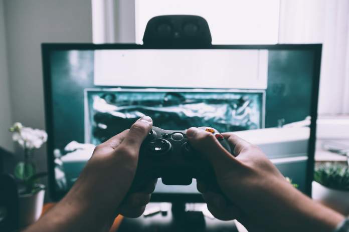 Manos con mando jugando a videojuegos
