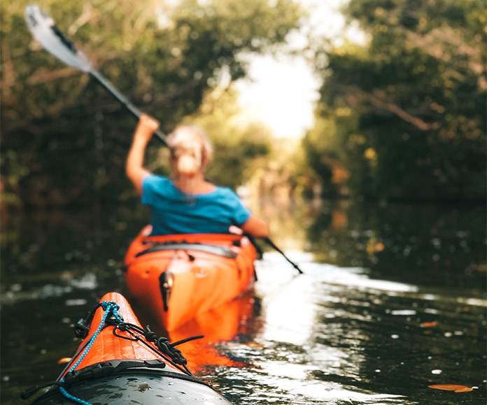 Mujer en kayak o canoa sosteniendo un remo