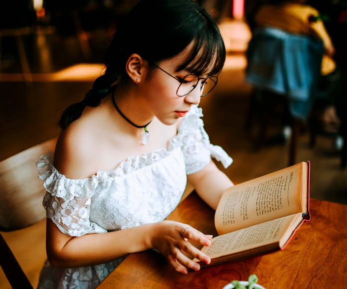 Chica leyendo un libro en un café.