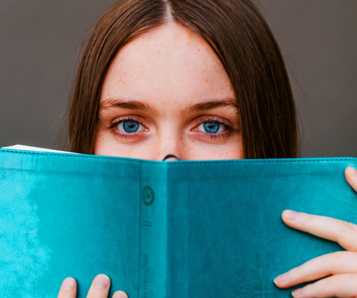 Chica asomándose detrás de un libro.