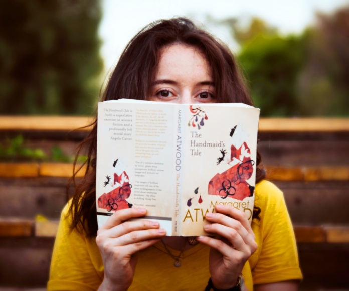 Mujer sosteniendo un libro frente a ella.