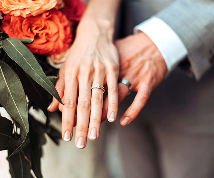 Manos superpuestas de pareja con anillos de boda