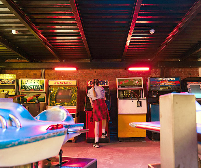 Adolescente de espaldas jugando a una máquina arcade