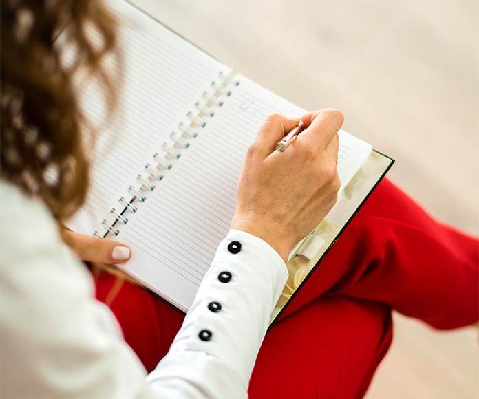 Mujer sentada escribiendo en un cuaderno