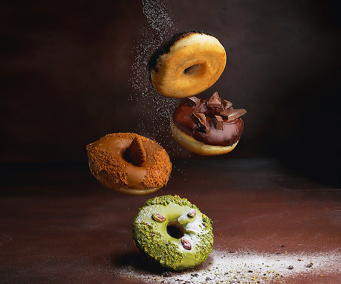 Donuts cayendo sobre una mesa de madera oscura