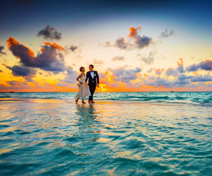 Pareja de casados caminando en la playa.