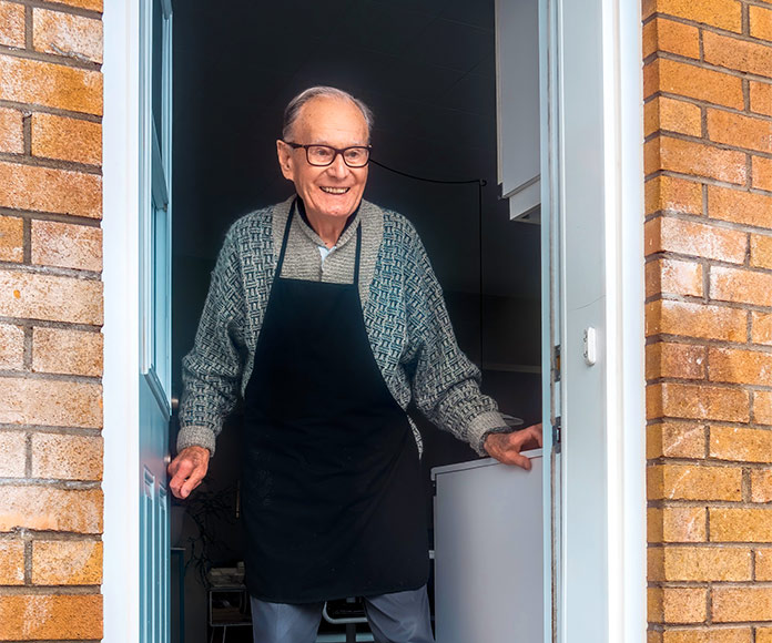 Hombre mayor abriendo la puerta de su casa