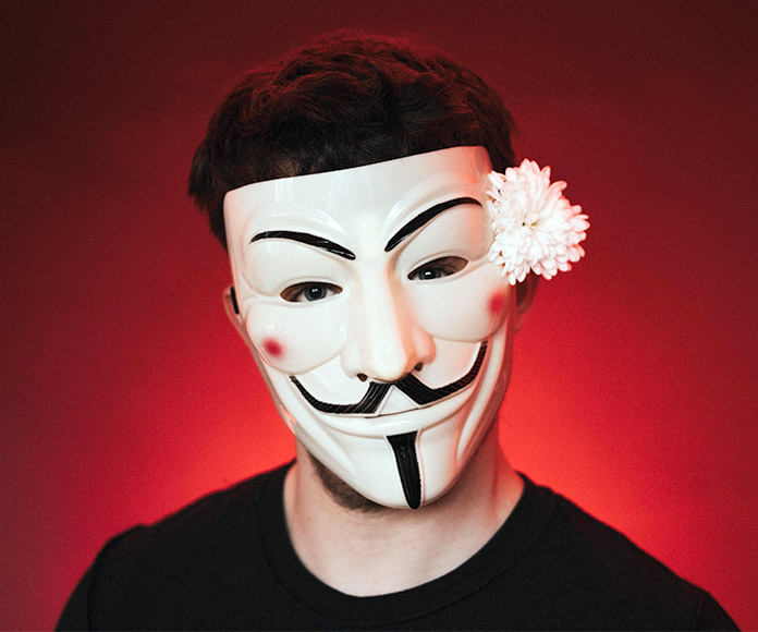 Hombre con máscara de Anonimus y flor en la oreja