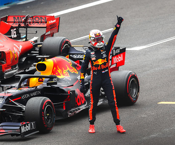 Piloto de Fórmula 1 levantando la mano victorioso al lado de su coche