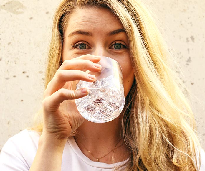 Mujer rubia bebiendo un vaso de agua