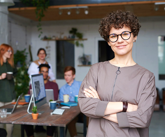 Mujer sonriente delante de un equipo de trabajo en oficina