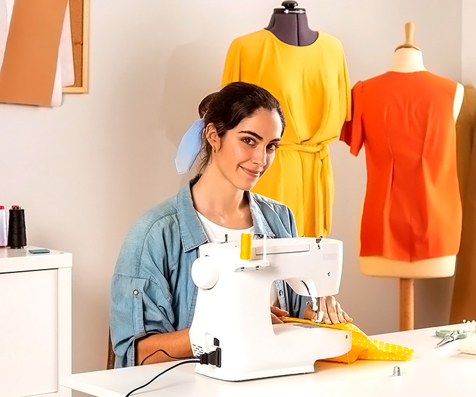 mujer sonriendo mientras usa una máquina de coser