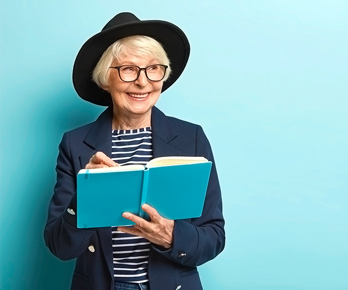 mujer mayor con sombrero negro leyendo un libro