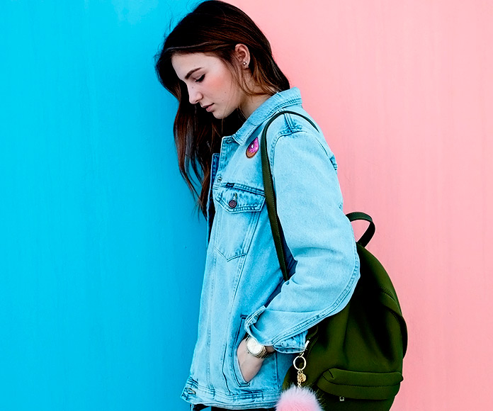 chica con mochila apoyada en una pared