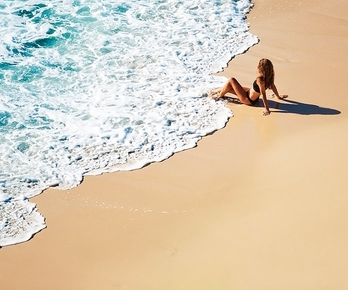 mujer mojándose los pies en la orilla de una playa