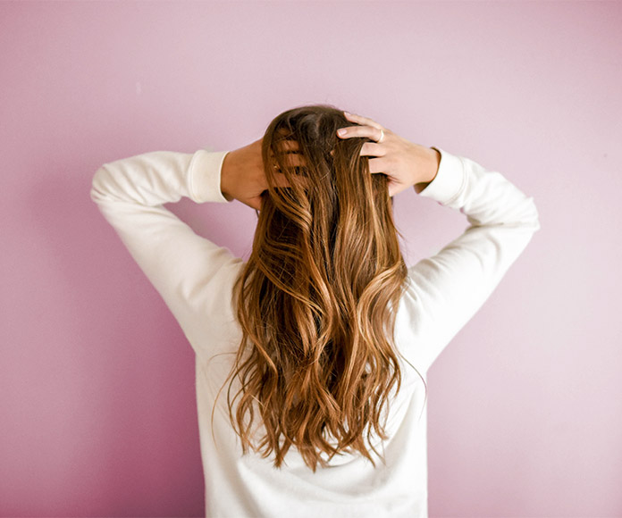 Mujer de espaldas tocándose el pelo