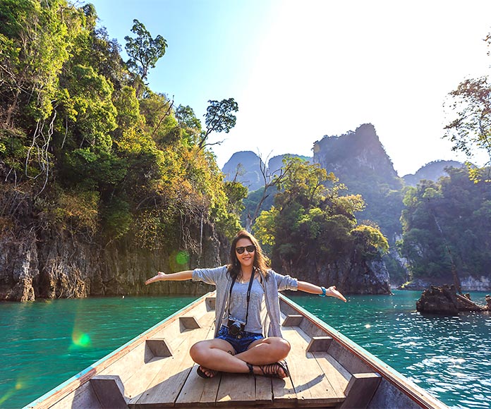 Mujer turista sentada en un barco con los brazos abiertos