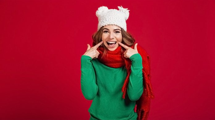 mujer sonriendo y señalando a su dentadura