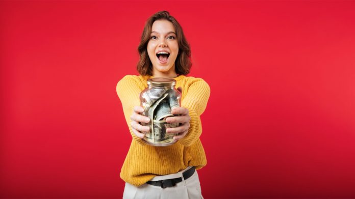 mujer feliz sujetando un tarro lleno de dinero