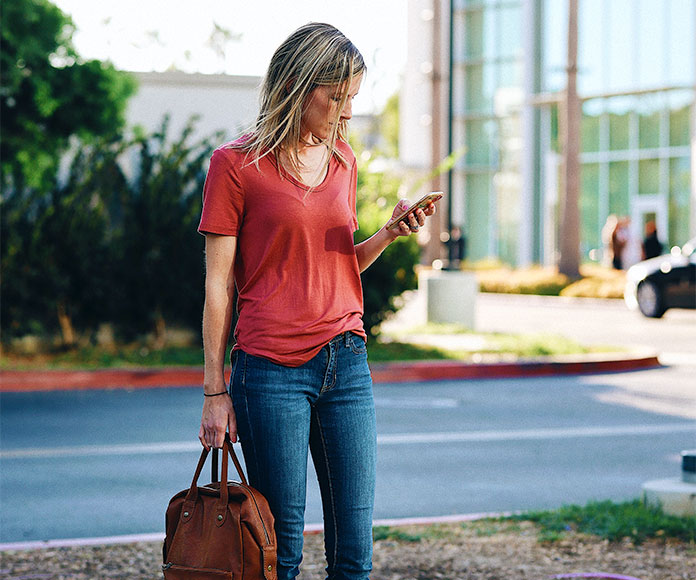 Mujer mirando su teléfono móvil en mitad de la calle