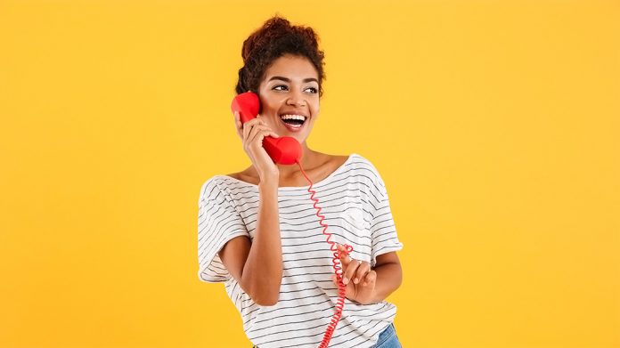 mujer sonriendo usando un teléfono rojo