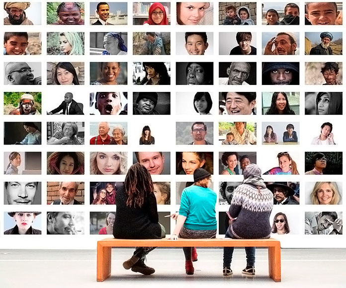 personas sentadas en un banco frente a un mural de fotografías