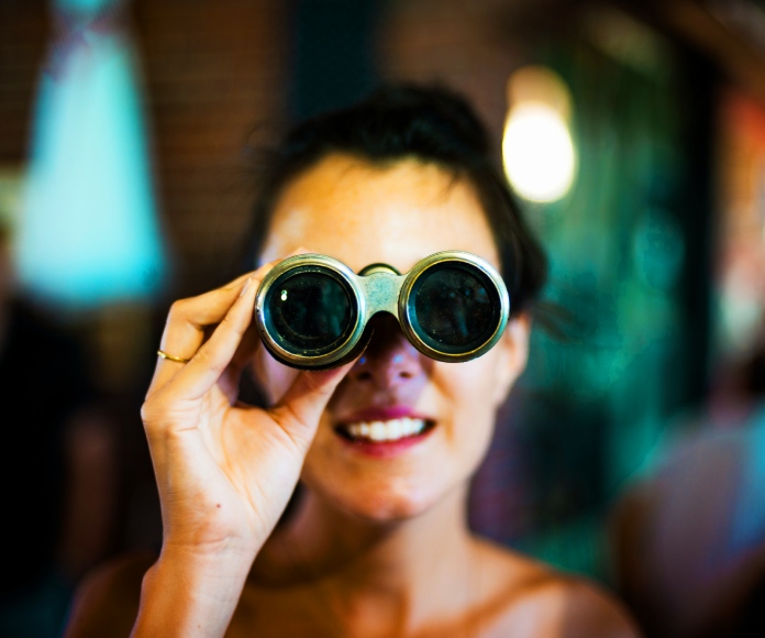 Mujer observando a través de unos binoculares.