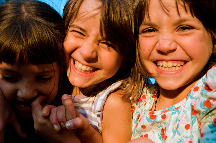 3 niñas cogidas de la mano sonriendo