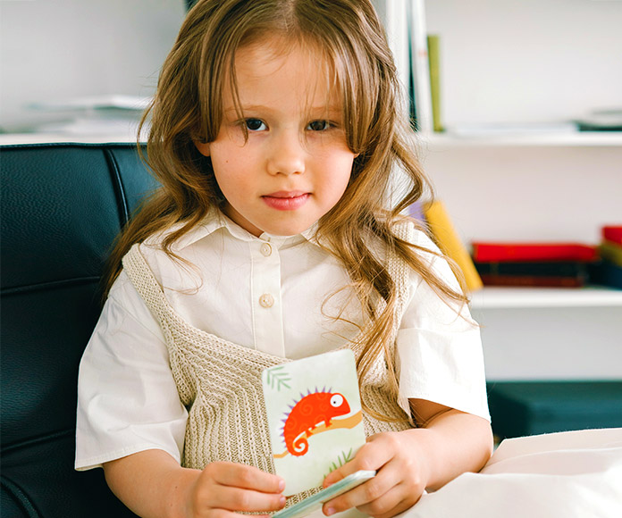 Niña mirando a cámara con una tarjeta de un animal