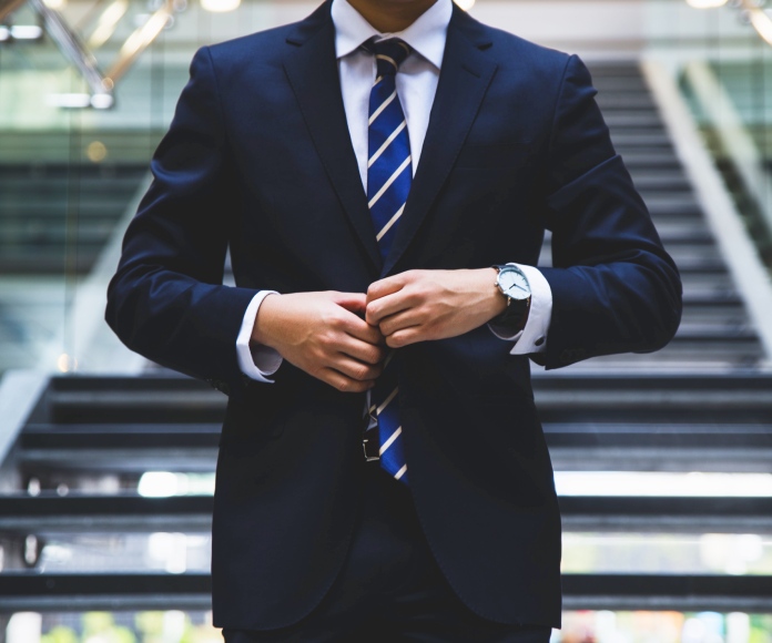 Hombre blanco abotonando su traje formal.