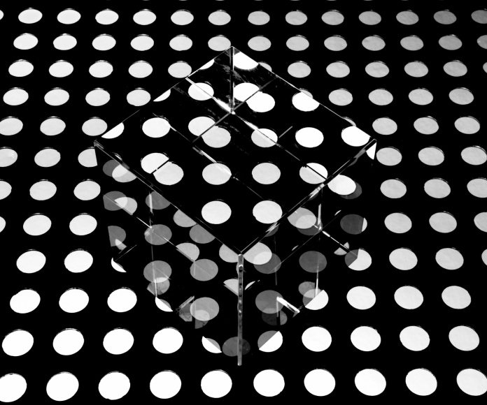 Un dado transparente en una superficie negra con puntos blancos.