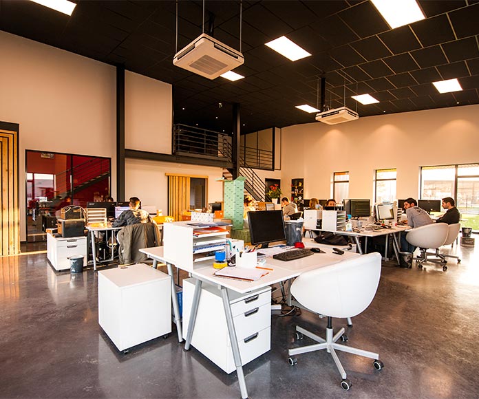 Oficina de empresa diáfana con mesas de trabajo, luces y aire acondicionado