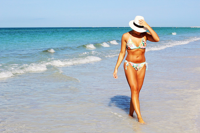 Mujer en traje de baño caminando en la playa 
