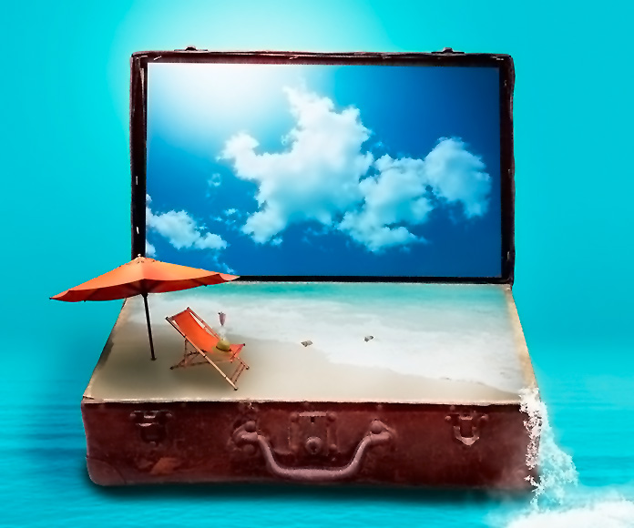 ordenador portátil sobre una maleta de viaje que simula una playa