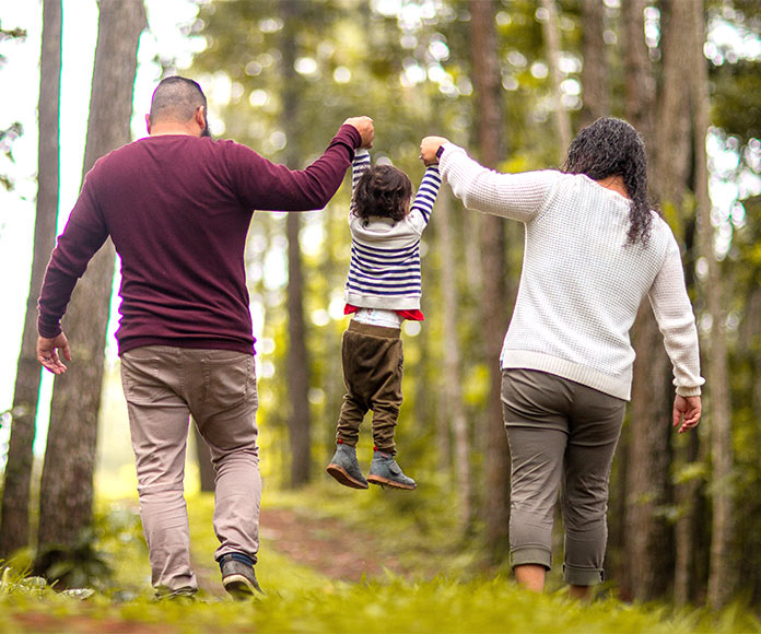 Padres en el bosque elevando a su hijo entre los dos